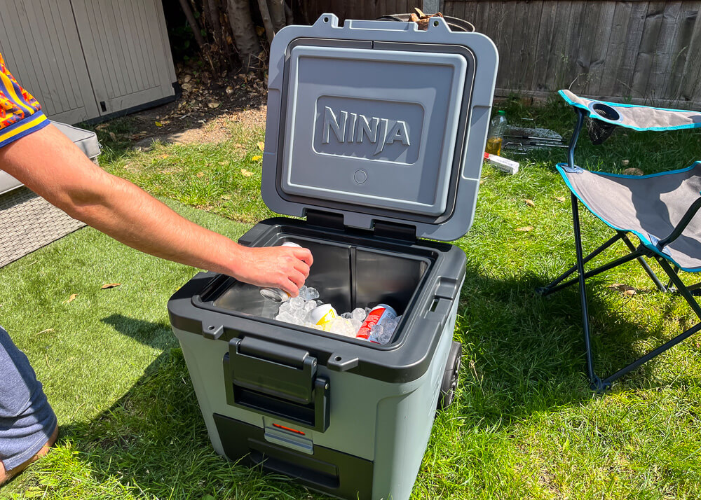 Hand reaching into an open cooler to grab a can