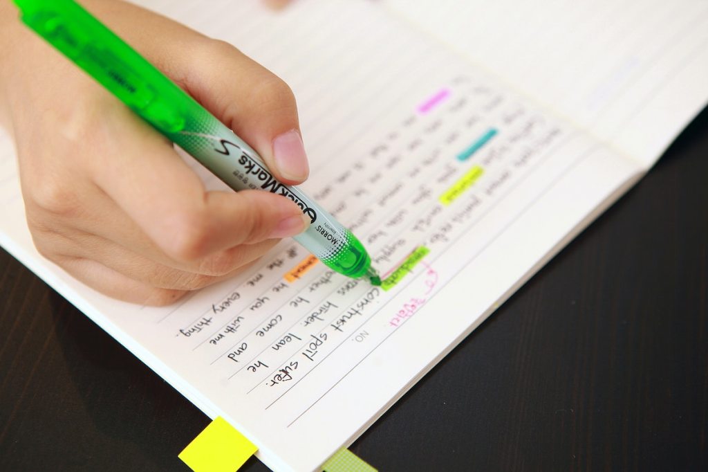 A hand highlighting words written in a notebook